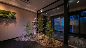 A modern interior with a stone water feature, bamboo plants, and a glass wall reflecting the outside.