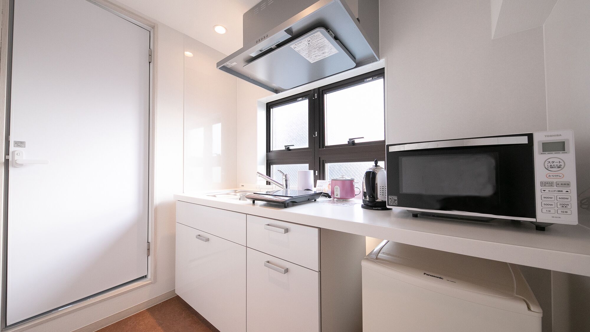Una kitchenette equipada con microondas, hervidor de agua y un refrigerador pequeño.