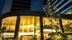 Entrada d'hotel moderna amb façana corba, grans finestres de vidre i interior ben il·luminat.