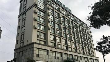 A multi-story hotel with a flat facade, large windows, and a green sign at the entrance.