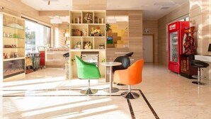 A modern lobby with a reception desk, a vending machine, and a green and orange seating area. - Greentree Inn Yancheng Tinghu Area Wanda Square Br (Yancheng)