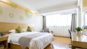 A hotel room with a bed, bedside table, chair, desk, and a window with curtains. - Greentree Inn Yancheng Tinghu Area Wanda Square Br (Yancheng)