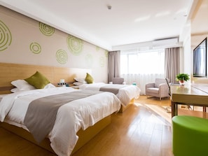 Ein Hotelzimmer mit zwei Betten, einem Schreibtisch, einem Sessel, einer Pflanze und einem Vorhangfenster.