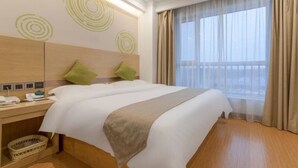 A hotel room with a double bed, a bedside table with a lamp, a small basket, and a window with curtains. - Greentree Inn Weifang Kuiwen District Beiwang Jial (Weifang)