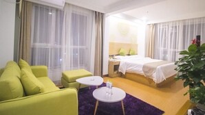 A hotel room with a bed, a green sofa, two small tables, and a large window with sheer curtains. - Greentree Inn Weifang Kuiwen District Beiwang Jial (Weifang)