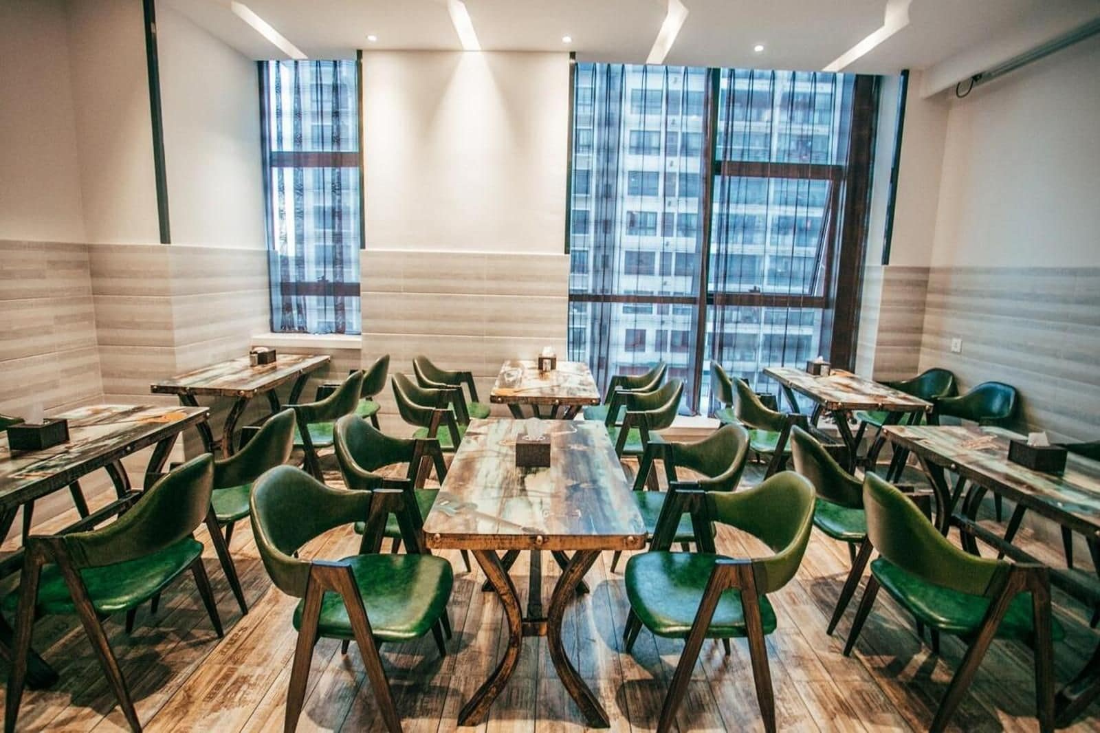 Un salón de conferencias con varias mesas y sillas, grandes ventanales con vista a la ciudad y un diseño de interiores moderno.
