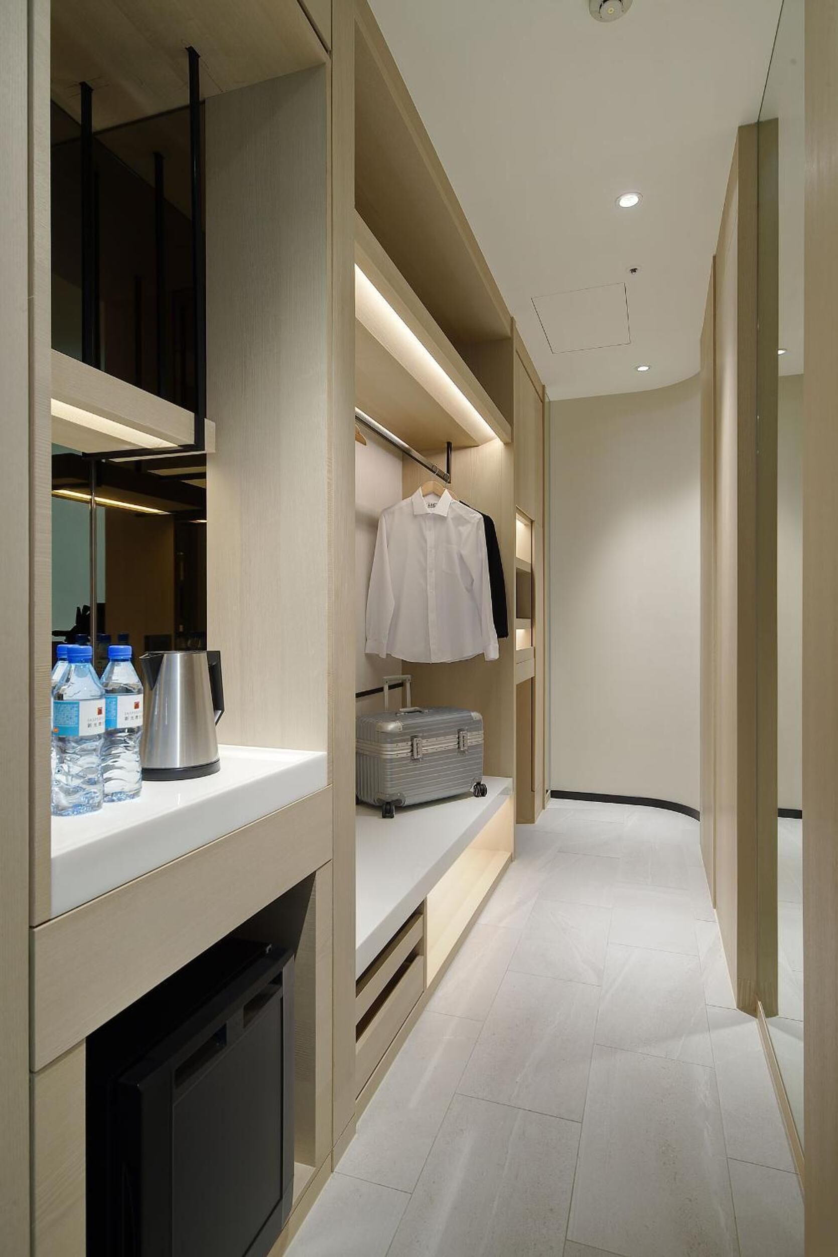 Habitación de hotel moderna con armario empotrado, minibar y zona de estar.
