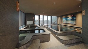 Ein moderner Wellnessbereich mit zwei Whirlpools, einer Holzbank und einem Gemälde des Fuji.