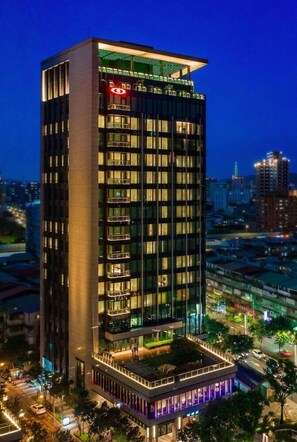 A high-rise hotel with multiple floors, large windows, and a rooftop garden.