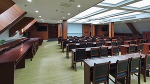 A conference room with long tables and chairs, a projector screen, and a wooden panel wall. - Greentree Inn Luoyang Train Station Zhuangyuanhong (Luoyang)