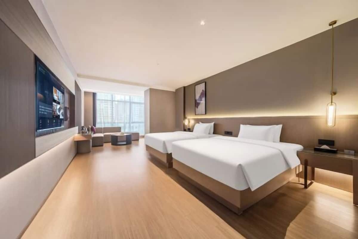 Une chambre d’hôtel moderne, dotée d’un grand lit, de tables de chevet, d’un bureau et d’une télévision.