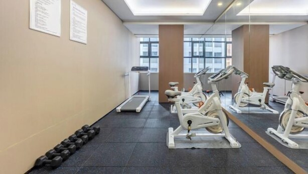 A gym with stationary bikes, a treadmill, and dumbbells. - LAVANDE HOTELS (Chaozhou)