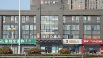 Un edificio de varios pisos con señalización para diversos negocios, incluyendo un hotel y un centro médico.
