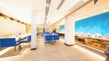Un amplio vestíbulo de hotel con un mostrador de recepción alargado, zona de estar en tonos azules y un gran acuario.