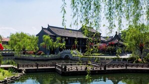 A traditional building with a tiled roof, a wooden bridge over a pond, and a stone pathway. - Jinjiang Inn Select (Huai'an Hexia Ancient Town Xiangyu Avenue) (Huai'an)