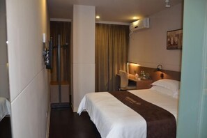 A hotel room with a bed, a desk, a chair, a nightstand, and a wall-mounted air conditioner. - Jinjiang Inn Select (Huai'an Hexia Ancient Town Xiangyu Avenue) (Huai'an)