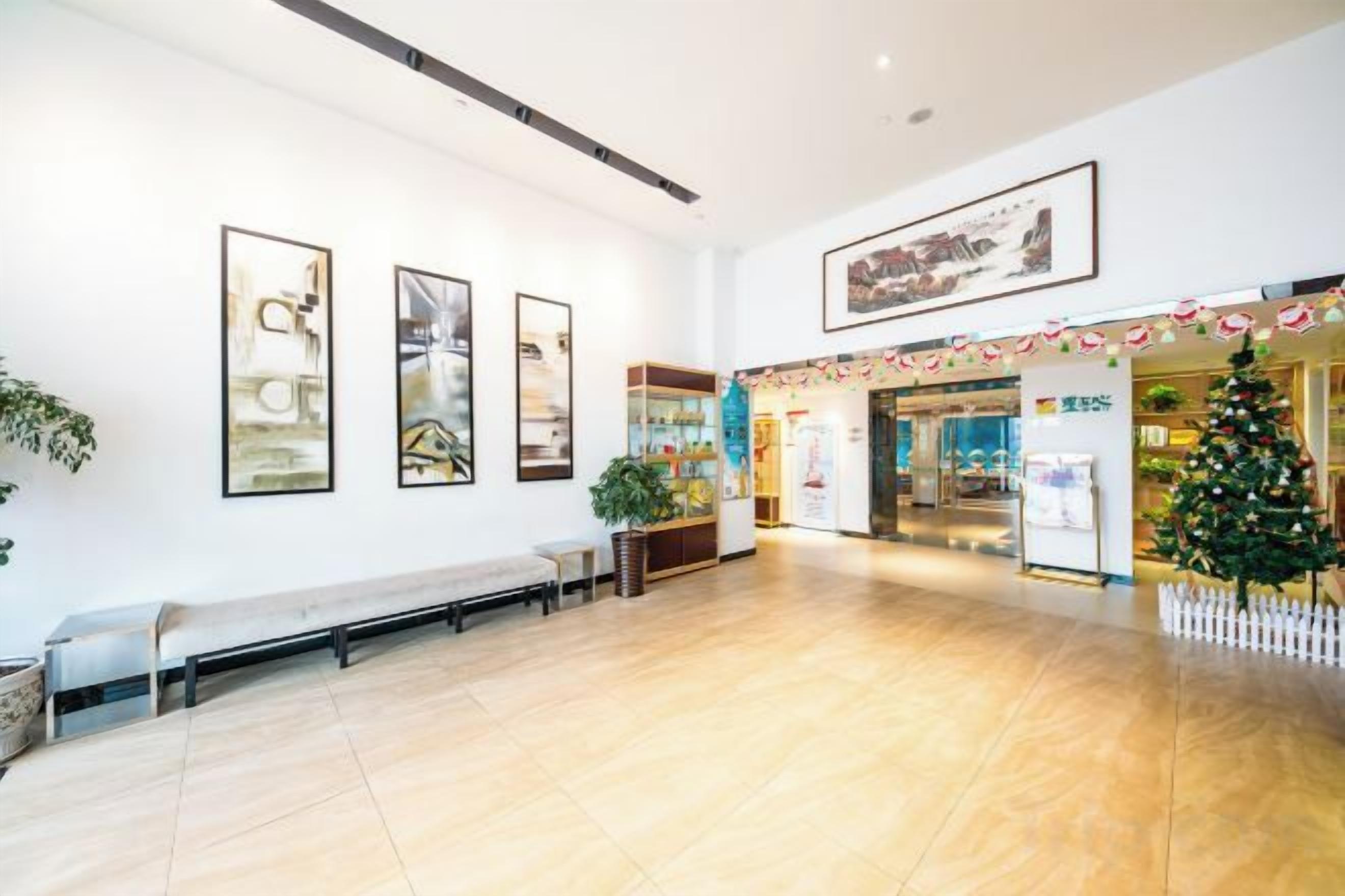 A spacious indoor area with a wooden floor, benches, and a Christmas tree.