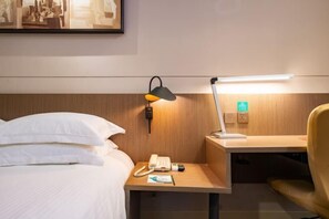 A hotel room with a bed, a bedside table with a lamp, a phone, and a small desk with a chair. - Jinjiang Inn Select (Huai'an Hexia Ancient Town Xiangyu Avenue) (Huai'an)