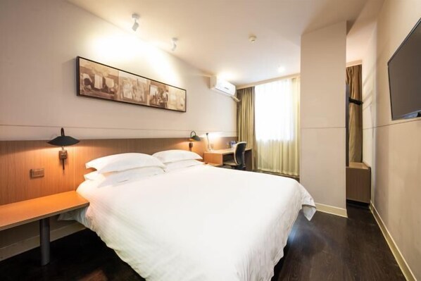 A hotel room with a large bed, a desk, a chair, a flat-screen TV, and a painting on the wall. - Jinjiang Inn Select (Huai'an Hexia Ancient Town Xiangyu Avenue) (Huai'an)