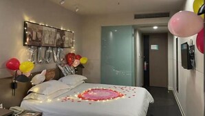 A hotel room with a bed, a wall-mounted photo collage, balloons, and a door leading to another room. - Jinjiang Inn Select (Huai'an Hexia Ancient Town Xiangyu Avenue) (Huai'an)