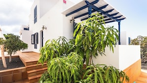 Um edifício moderno com fachada branca, detalhes azuis e uma área externa coberta com degraus até a porta.
