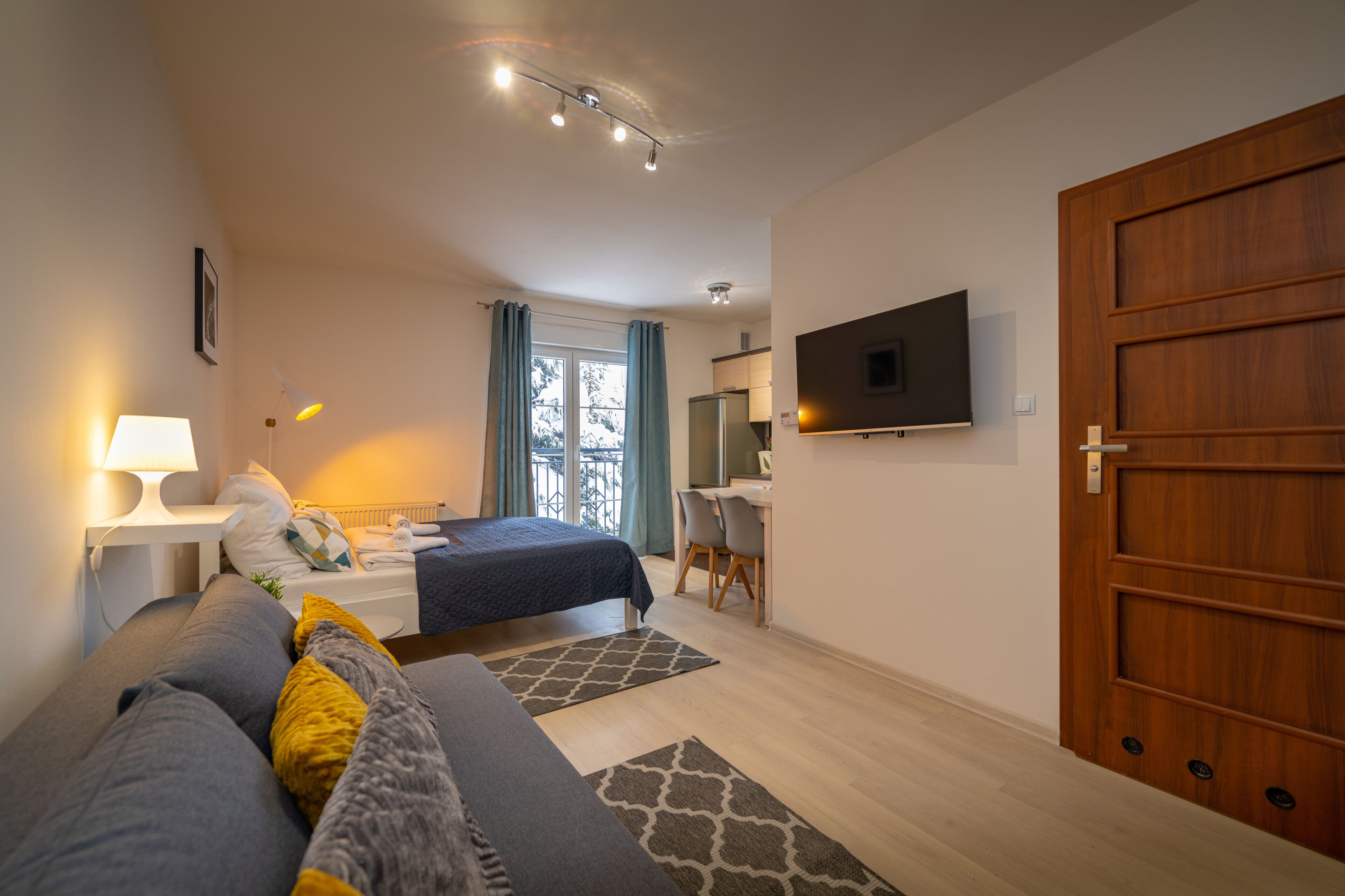 Ein modernes Schlafzimmer mit Bett, Nachttisch, Lampe und Fernseher an der Wand.