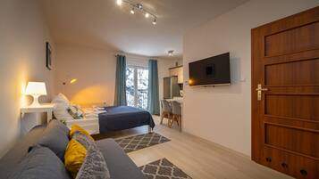 Ein modernes Schlafzimmer mit Bett, Nachttisch, Lampe und Fernseher an der Wand.
