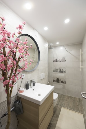 A modern bathroom with a white vanity, a round mirror, and a shower with a cityscape tile backsplash. - Casa Da Ponte (Koper)