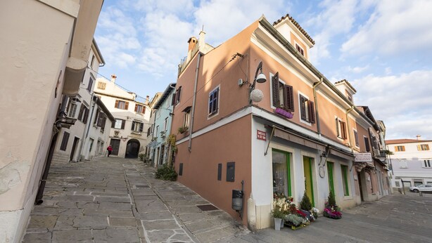 A narrow street with buildings on either side, featuring a shop with a sign that reads "MAIDANA". - Casa Da Ponte (Koper)
