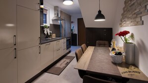 A modern kitchen with a dining area, featuring a wooden table, chairs, and a vase with flowers. - Casa Da Ponte (Koper)