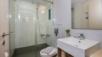 A modern bathroom with a glass-enclosed shower, a white sink, and a mirror above it.