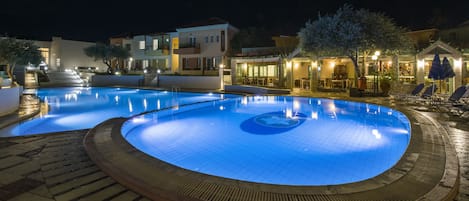 A swimming pool with a circular design, surrounded by a paved deck.