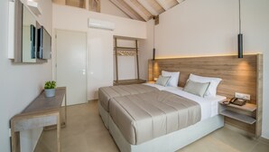 A modern bedroom with a large bed, bedside tables, a mirror, and a hanging light fixture. - Stefan Village Hotel (Chania)