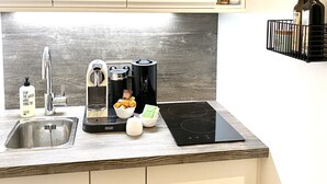 A modern kitchen with a stainless steel sink, a coffee maker, a toaster, and an induction cooktop. - Grace-Design-Apartment Deluxe in the center of Munich, top location (München)