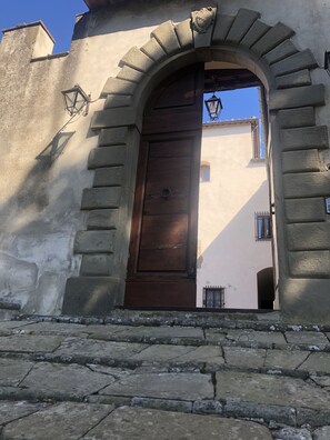 Traditional stone archway leads to a simple wooden door with a metal handle.
