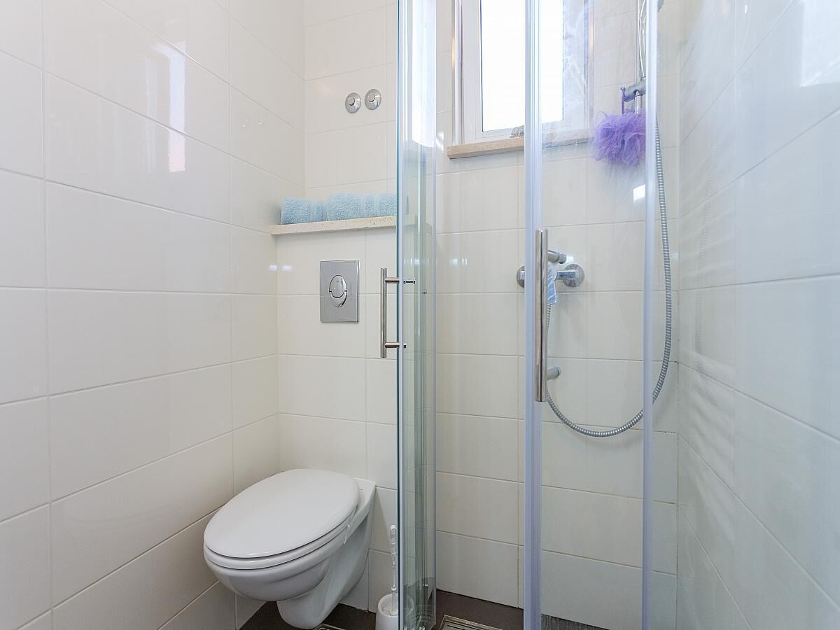 A bathroom with a toilet, a glass-enclosed shower, and a window.
