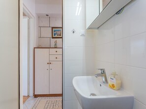 Une salle de bain avec un lavabo blanc, un miroir et un flacon de savon Cien.