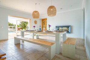 A modern kitchen with a central island, white benches, and hanging wicker pendant lights. - Tiny Whale Lodge, a unique space for groups (Lagos)