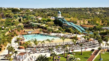 A resort with a large pool, multiple water slides, and a beach area with sun loungers.