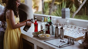 A bar area with bottles, glasses, and a person pouring a drink. - The Eden Lodge, a unique space for groups (Lagos)