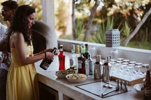 A bar area with bottles, glasses, and a person pouring a drink. - Tiny Whale Lodge, a unique space for groups (Lagos)