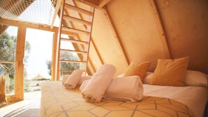 A wooden room with a bed, pillows, and towels. - The Eden Lodge, a unique space for groups (Lagos)
