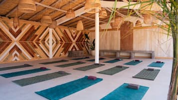 A yoga studio with wooden walls, tatami mats, and hanging rattan lamps.