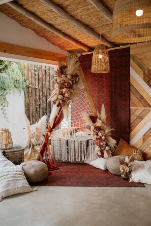 A rustic interior with a woven ceiling, a red patterned wall, and a decorative arrangement of flowers and feathers. - Tiny Whale Lodge, a unique space for groups (Lagos)