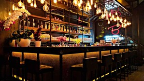 A bar area with multiple seating arrangements, shelves with bottles, and hanging light bulbs. - The Eden Lodge, a unique space for groups (Lagos)