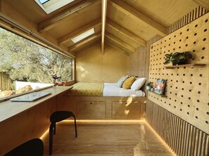 Une petite pièce en bois, avec un lit, un bureau et une chaise.