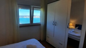 A hotel room with a bed, a wardrobe, and a window with a view of the sea. - Apartment with sea view and next to the beach (20m) (Betina)