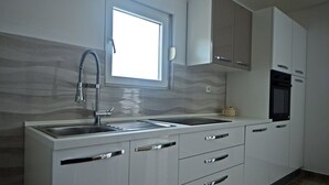 A modern kitchen with a double sink, stainless steel faucet, and white cabinetry. - Apartment with sea view and next to the beach (20m) (Betina)