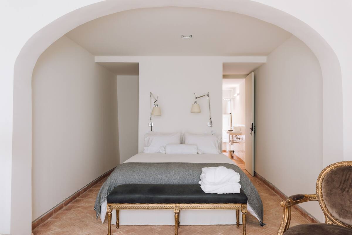 A bedroom with a large bed, a bench, and a chair.