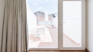 A room with a sliding glass door leading to an outdoor patio with a table and chairs. - Travassos 11 (Elvas)